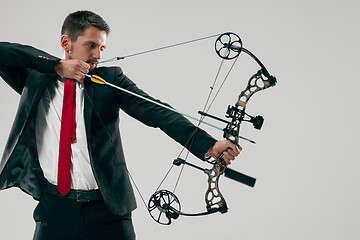 Image showing Businessman aiming at target with bow and arrow, isolated on white background