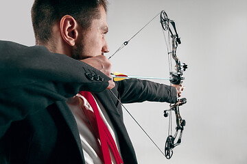 Image showing Businessman aiming at target with bow and arrow, isolated on white background