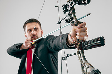 Image showing Businessman aiming at target with bow and arrow, isolated on white background