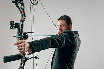 Image showing Businessman aiming at target with bow and arrow, isolated on white background