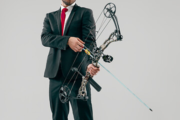 Image showing Businessman aiming at target with bow and arrow, isolated on white background