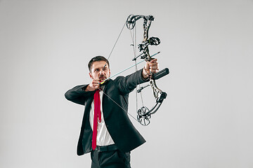 Image showing Businessman aiming at target with bow and arrow, isolated on white background