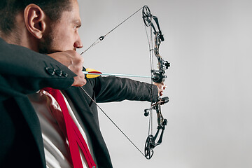 Image showing Businessman aiming at target with bow and arrow, isolated on white background