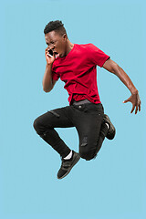 Image showing always on mobile. Full length of handsome young man taking phone while jumping