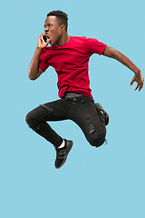 Image showing always on mobile. Full length of handsome young man taking phone while jumping