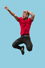 Image showing Freedom in moving and forward motion. The happy surprised young afro man jumping