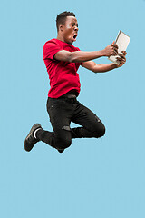 Image showing Image of happy excited young african man jumping isolated over yellow background using laptop