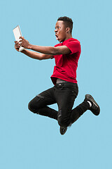 Image showing Image of happy excited young african man jumping isolated over yellow background using laptop