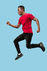 Image showing Freedom in moving and forward motion. The happy surprised young afro man jumping