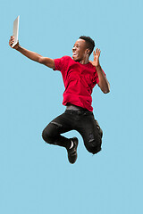 Image showing Image of happy excited young african man jumping isolated over yellow background using laptop