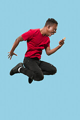 Image showing always on mobile. Full length of handsome young man taking phone while jumping