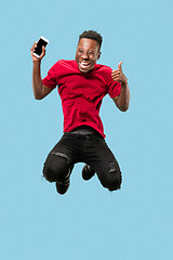 Image showing always on mobile. Full length of handsome young man taking phone while jumping