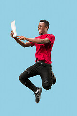 Image showing Image of happy excited young african man jumping isolated over yellow background using laptop