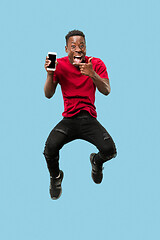 Image showing always on mobile. Full length of handsome young man taking phone while jumping