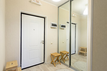 Image showing Entrance hall interior with metal front door and large sliding wardrobe with mirrors