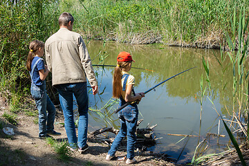 Image showing Dad with two daughters fishing on a lake