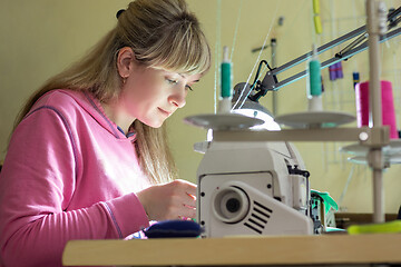 Image showing Girl happily sews on a professional sewing machine