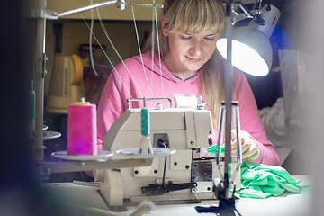 Image showing Girl works by light lamp behind industrial sewing machine