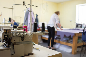 Image showing sewing equipment in the workshop and seamstress in the background