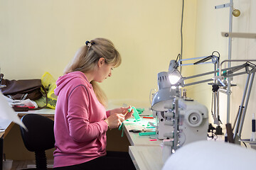 Image showing Professional seamstress makes an element of clothing in the workplace