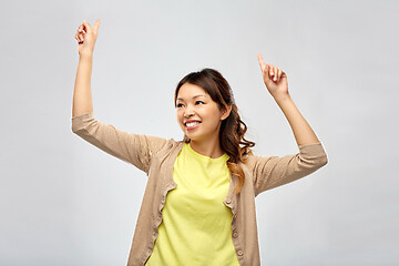 Image showing happy asian woman dancing over grey background