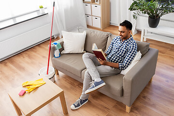 Image showing man reading book and resting after home cleaning