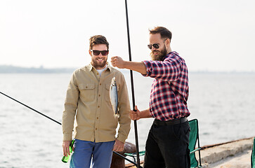 Image showing male friends with fishing rods and beer on pier