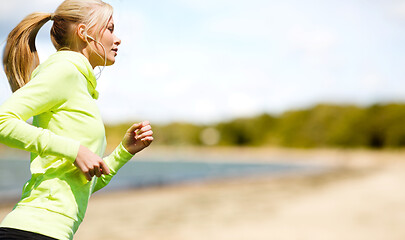 Image showing woman with earphones running at park