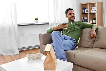 Image showing indian man with takeaway coffee and food at home