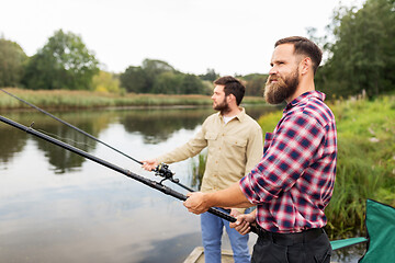 Image showing male friends with fishing rods on lake pier