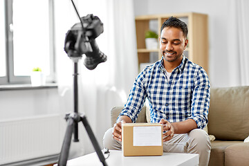 Image showing male video blogger opening parcel box at home