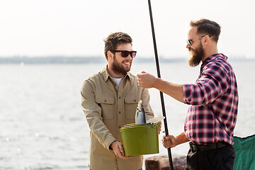 Image showing male friends with fish and fishing rods on pier