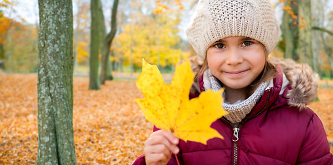 Image showing happy girl with fallen maple leaf at autumn park