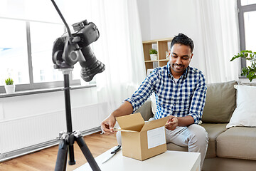 Image showing male video blogger opening parcel box at home