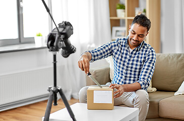 Image showing male video blogger opening parcel box at home