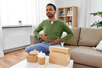 Image showing pleased indian man eating takeaway food at home