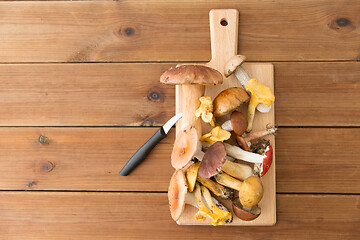 Image showing edible mushrooms on wooden cutting board and knife