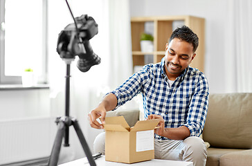 Image showing male video blogger opening parcel box at home