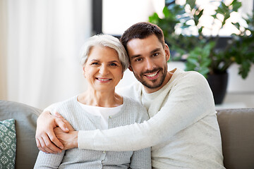 Image showing senior mother with adult son hugging at home