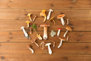 Image showing different edible mushrooms on wooden background