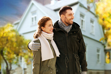 Image showing smiling couple hugging over house in autumn