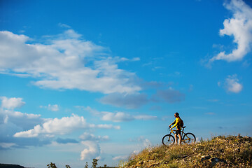 Image showing Cyclist riding a bike on off road to the sunset