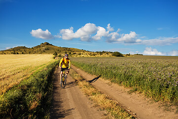 Image showing Cyclist riding a bike on off road to the sunset