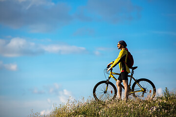 Image showing Cyclist riding a bike on off road to the sunset