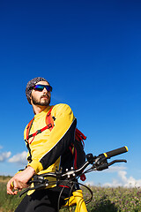 Image showing Cyclist riding a bike on off road to the sunset