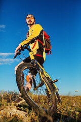 Image showing Cyclist man standing on top of a mountain with bicycle