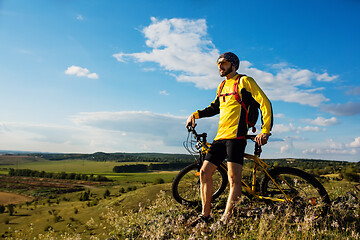 Image showing Cyclist riding a bike on off road to the sunset