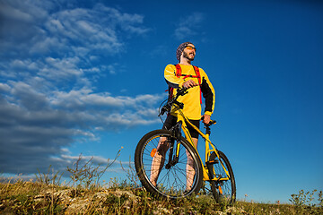 Image showing Cyclist man standing on top of a mountain with bicycle