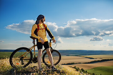 Image showing Cyclist riding a bike on off road to the sunset