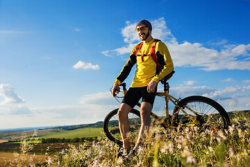 Image showing Cyclist riding a bike on off road to the sunset